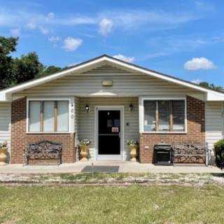 A single-story house with a brick exterior, featuring benches and a clear blue sky.