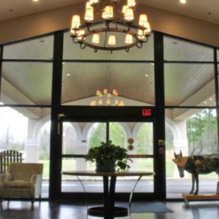 A lobby interior with a large chandelier, glass doors, and elegant furniture.