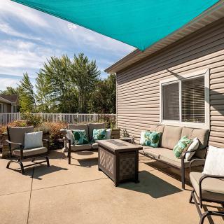 A cozy outdoor patio with comfortable seating and a sunshade.