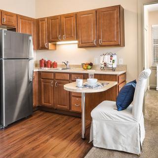 A cozy modern kitchen with wooden cabinets and a stainless steel refrigerator.