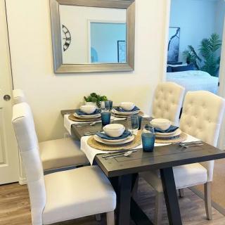 A neatly arranged dining table with elegant place settings and cushioned chairs.