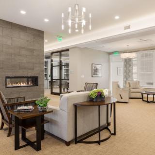 A modern living room with elegant dcor, featuring a fireplace, comfortable seating, and a stylish chandelier.