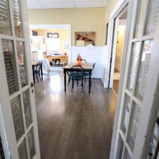 A view into a dining room with hardwood floors and open French doors.