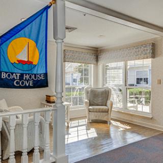 A cozy living room with ample sunlight, featuring a nautical-themed flag and a comfortable seating area.