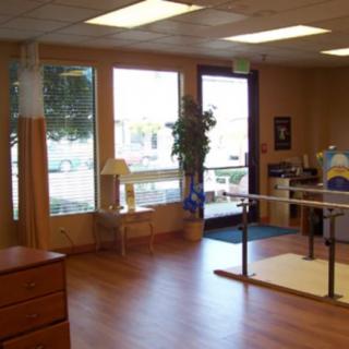 A well-lit rehabilitation center featuring parallel bars for physical therapy exercises.