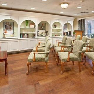 A well-arranged seating area with armchairs and bookshelves in a warmly lit room.