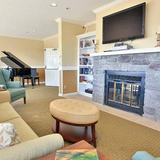 A cozy living room featuring a fireplace with a mounted television, bookshelves, and a grand piano.