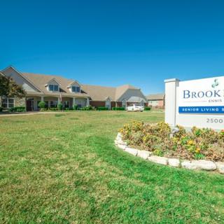 A well-maintained building with a sign and landscaped lawn beneath a clear blue sky.