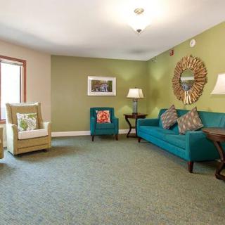 A cozy living room with a teal sofa, armchair, and stylish decor.