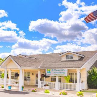 A small building with an American flag flying, set against a blue sky with fluffy clouds.