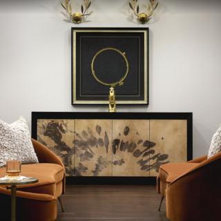 A contemporary lounge area featuring stylish armchairs, a unique sideboard with artistic patterns, and sophisticated wall art.
