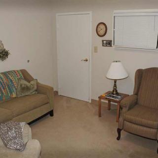 A cozy living room with a sofa, armchair, and a small table with a lamp.