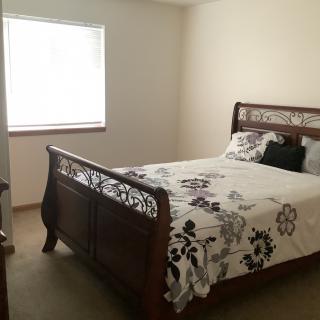 A cozy bedroom with a wooden bed frame and floral bedding.