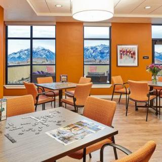 A modern dining area with orange walls and large windows showcasing a scenic mountain view.