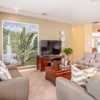 A cozy and modern living room featuring comfortable sofas, a large television, and vibrant wall art.