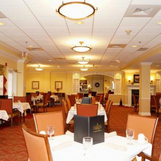 An elegant restaurant dining area with neatly arranged tables and chairs, soft lighting, and a menu placed on one of the tables.