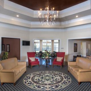 A spacious, well-lit living room featuring elegant furniture and a central chandelier.