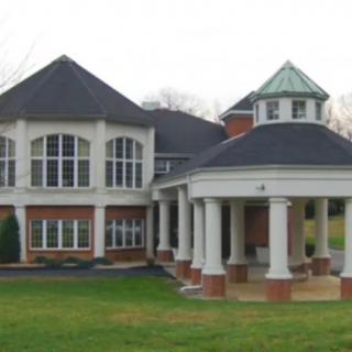 A large house with prominent columns and a spacious lawn.
