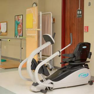 A recumbent exercise bike in a healthcare facility gym area.
