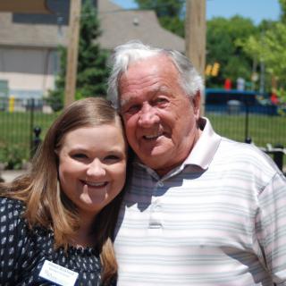 A smiling elderly man and a young woman enjoy a sunny day in the park.
