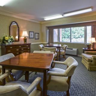A cozy living room with comfortable chairs and tables, featuring warm lighting and elegant decor.