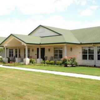A single-story house with a green roof and a well-maintained lawn.