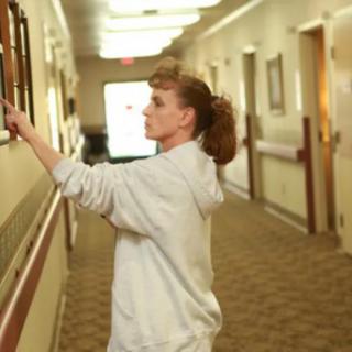 A nurse adjusting a display in a hospital hallway.