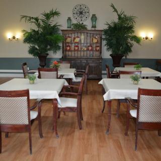 A well-decorated dining area with tables and chairs, adorned with plants and subtle lighting.