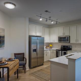 A modern kitchen with stainless steel appliances and a small dining area.