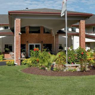 A well-maintained building entrance with a flagpole and landscaped garden.