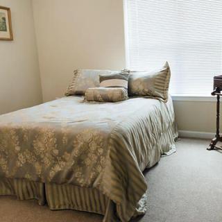 A neatly arranged bedroom with a bed and pillows next to a window.