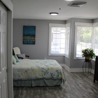 A bright and modern bedroom with large windows, a bed, and simple decor.