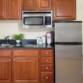 A modern kitchen with wooden cabinets, a stainless steel refrigerator, and a microwave above the counter.