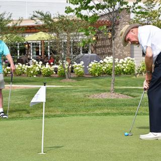 Two men playing golf on a putting green at a golf course.