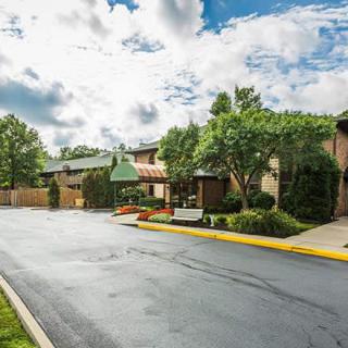 A well-maintained suburban building with trees and a paved road under a partly cloudy sky.
