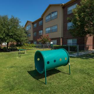 An apartment building with a green outdoor area featuring playground equipment.