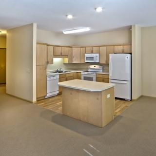 A modern kitchen with wooden cabinets, a central island, and various appliances.
