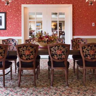 A traditional dining room with floral upholstered chairs, a large table, and elegant chandeliers.