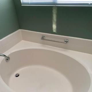 A clean, oval-shaped bathtub with a faucet in a bathroom setting.