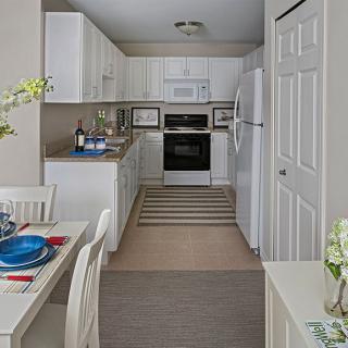 A modern kitchen with white cabinets and a small dining area.