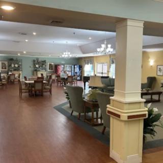 A spacious lounge area in a senior living facility with comfortable seating and elegant lighting.