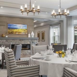 An elegantly designed dining room with chandeliers, a fireplace, and neatly set tables.