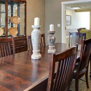A dining room with a wooden table and chairs, featuring candles and a china cabinet.