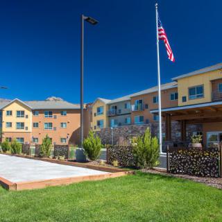 A modern hotel with a lush lawn and an American flag flying outside.