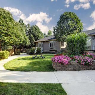 A charming house surrounded by a well-maintained garden with a winding pathway and vibrant flowers.