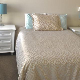 A neatly arranged bedroom with a bed, two nightstands, and matching lamps.