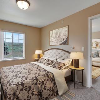 A cozy and elegantly decorated bedroom featuring a comfortable bed, stylish lamps, and decorative wall art.