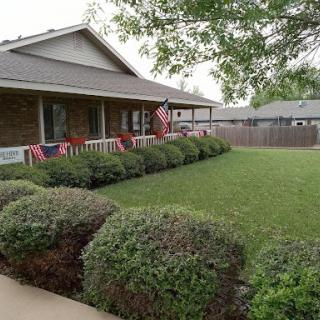 A well-maintained front yard featuring lush green grass and decorative American flags.