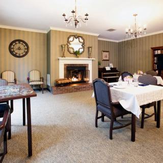 A classic dining room featuring chandeliers and a fireplace, with elegantly set tables and chairs.