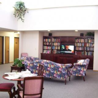 A cozy library space with bookshelves, floral couches, and a small table with chairs.